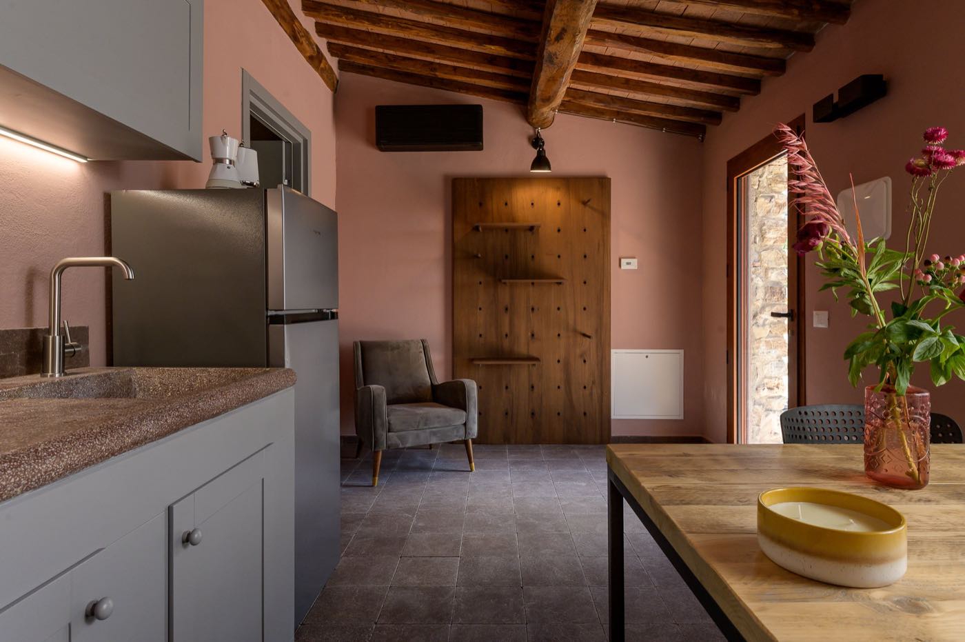 Appartamento con pareti rosa, travi a vista e angolo cottura