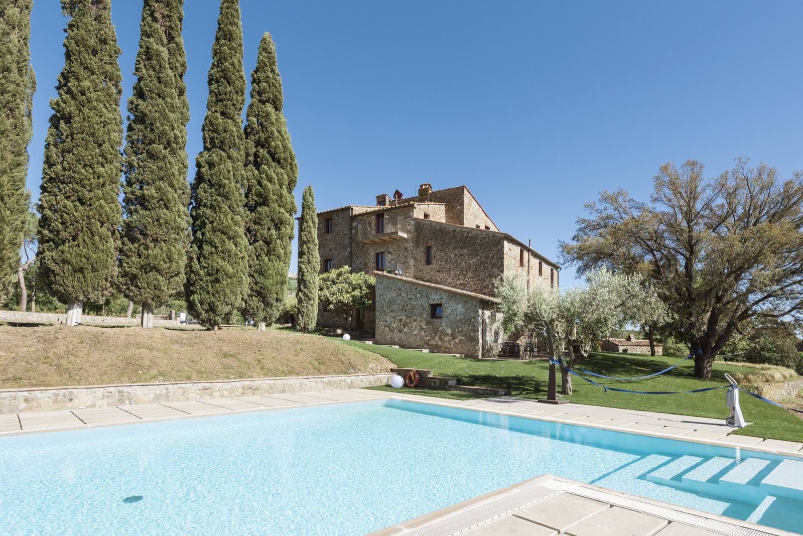 La piscina e i cipressi davanti al casale